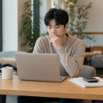 노트북으로 자격증 시험 정보를 확인하며 고민하는 청년의 모습