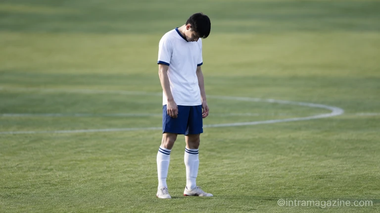 경기 도중 실망한 표정으로 잔디 위에 서 있는 축구 선수의 모습