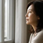 창밖을 보며 생각에 잠긴 중년 여성