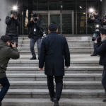 법원 청사 입구에서 취재진 사이로 출석하는 피의자의 모습