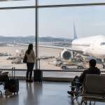 국제공항 탑승구 앞에서 대기 중인 승객들과 창밖의 여객기