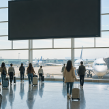 국제공항 대형 안내 전광판과 이동하는 여행객들의 모습
